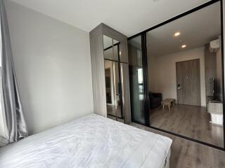 Modern bedroom with large glass wardrobe and view into an adjacent living area