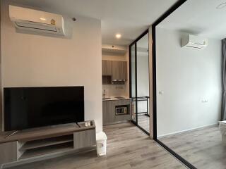 Modern living room with TV, kitchen, and glass partition