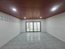 Spacious empty room with tile flooring and wooden ceiling