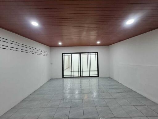 Spacious empty room with tile flooring and wooden ceiling