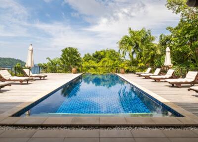 Luxurious outdoor swimming pool area with sun loungers and umbrellas