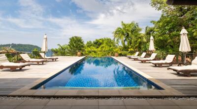 Luxurious outdoor swimming pool area with sun loungers and umbrellas