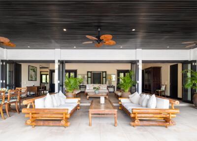 Spacious open-concept living area with elegant wooden furniture and ceiling fans