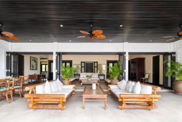 Spacious open-concept living area with elegant wooden furniture and ceiling fans