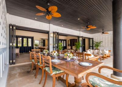 Spacious indoor-outdoor dining area with wooden table and ceiling fans