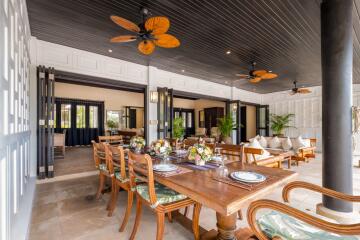 Spacious indoor-outdoor dining area with wooden table and ceiling fans