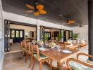 Spacious indoor-outdoor dining area with wooden table and ceiling fans