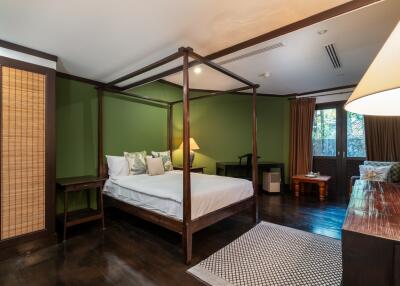 Bedroom with green walls, large bed, and wooden furniture