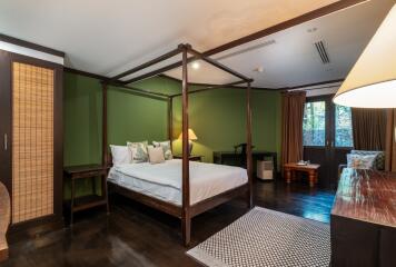 Bedroom with green walls, large bed, and wooden furniture