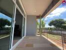 spacious balcony with a view of trees and a partially covered ceiling