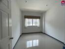 Empty room with a window and tiled flooring