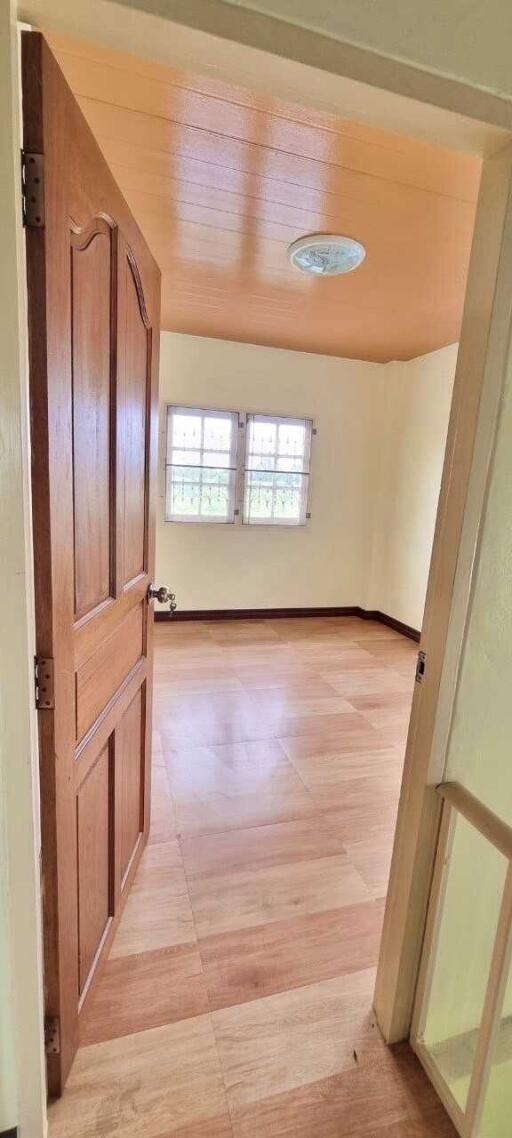 Spacious bedroom with wooden door and natural lighting