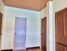 Hallway with three wooden doors and light-colored walls