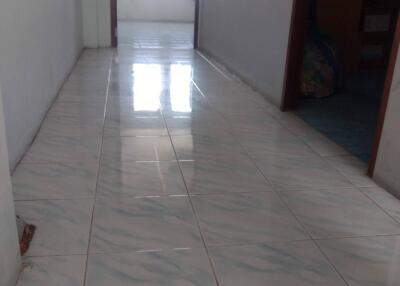 Hallway with tiled floor leading to a room with a window