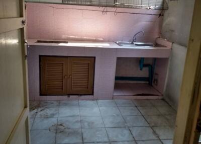 Basic kitchen with tiled floor, sink, countertop, and wall shelves