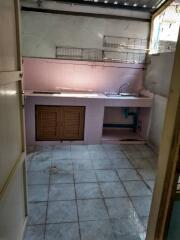 Basic kitchen with tiled floor, sink, countertop, and wall shelves