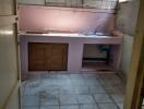 Basic kitchen with tiled floor, sink, countertop, and wall shelves