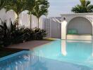 Outdoor pool with seating area surrounded by greenery