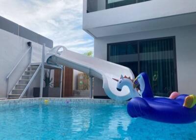 Modern outdoor swimming pool with a slide and inflatable floaties