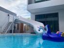 Modern outdoor swimming pool with a slide and inflatable floaties