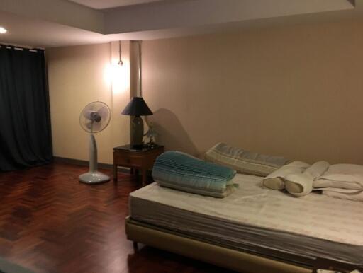 Bedroom with unmade bed, a fan, a nightstand, and a lamp