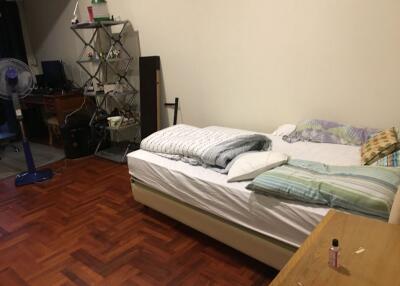 Photograph of a bedroom with a bed, shelves, and a desk