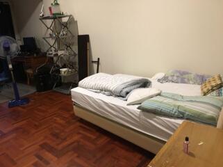 Photograph of a bedroom with a bed, shelves, and a desk