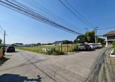 Street view of a residential area with parked cars and vacant lot