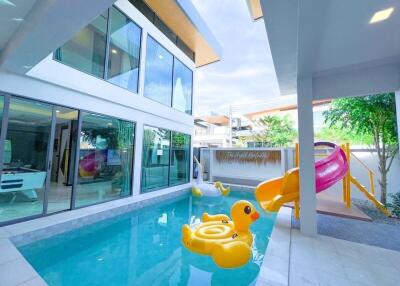 Outdoor pool area with slide and inflatable toys in a modern home