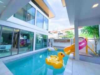 Outdoor pool area with slide and inflatable toys in a modern home