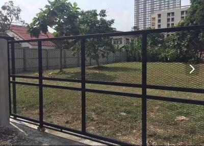 Gated garden area with trees and buildings in the background