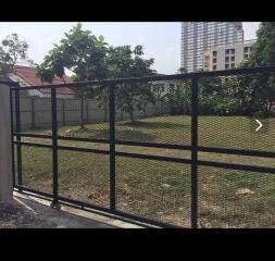 Gated garden area with trees and buildings in the background