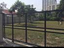 Gated garden area with trees and buildings in the background