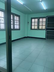 An empty room with tiled floor, barred windows, and fluorescent lighting