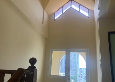 Staircase leading to a balcony with a high ceiling and natural light