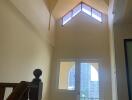 Staircase leading to a balcony with a high ceiling and natural light