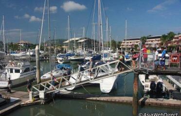 marina with several boats docked and people walking on a bridge