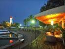 Outdoor deck area by the waterfront with seating and nearby lighthouse