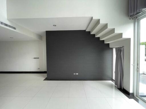 Modern living room with staircase and large windows