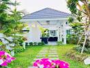 Beautiful garden with a pathway leading to the house, surrounded by flowering plants and trees.