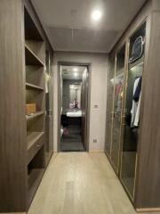 Walk-in closet with shelves, glass-front cabinets, and an en-suite bathroom