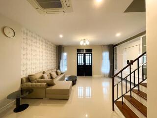 Modern living room with sectional sofa, stairs, and decorative wall