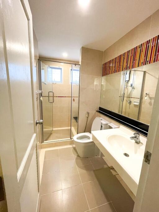 Modern bathroom with glass shower, large mirror, and white fixtures