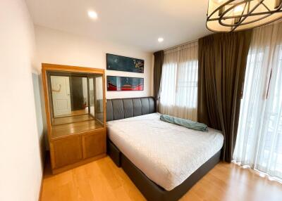 Bedroom with large bed, wooden flooring, a wardrobe and large windows with curtains