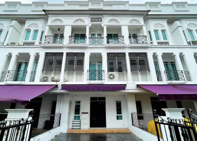 Exterior of a multi-story residential building with balconies and purple awnings