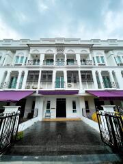 Exterior of a multi-story residential building with balconies and purple awnings