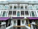 Exterior of a multi-story residential building with balconies and purple awnings