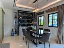 Modern dining room with glass table and six chairs, large windows, and built-in shelves