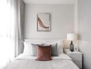 A modern bedroom with a neatly made bed, nightstand, lamp, and wall art