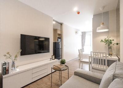Modern living room with a TV, light-colored furniture, dining area, and cozy decor